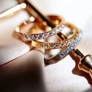 Three-color titanium steel eternity rings with CNC set crystals on a soft satin background