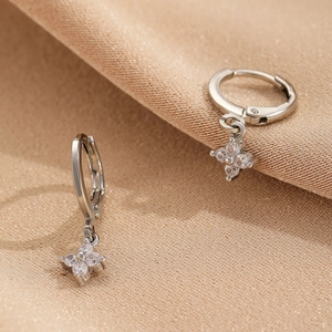 Macro shot of silver star stud earrings with zircon crystals on champagne silk background
