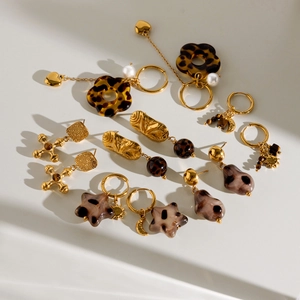 Parure de boucles d'oreilles dorées rétro avec perles et motifs léopard sur fond blanc