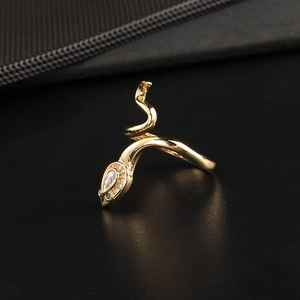 Detailed close-up of a golden snake ring with white diamonds and green gemstone eyes