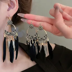 Boucles d'oreilles bohèmes avec plumes noires et cadre doré orné de gemmes noires