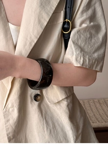 Macro detail of wide resin bangle with dark marble pattern on model wrist