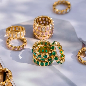 Luxurious gold rings set with emerald and pink stones in a high-fashion lifestyle arrangement