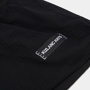 Close-up of the black knitted fabric texture and KIZLANC HATS woven label on the beanie