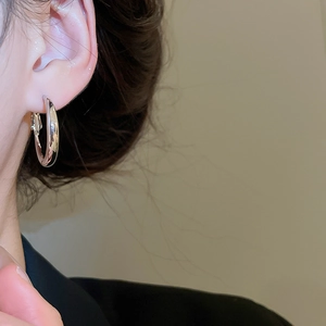 Close-up of minimalist silver hoop earrings worn on ear in a clean lighting setup