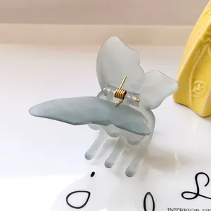 Macro shot of light blue matte butterfly hair claw clip with golden metal spring