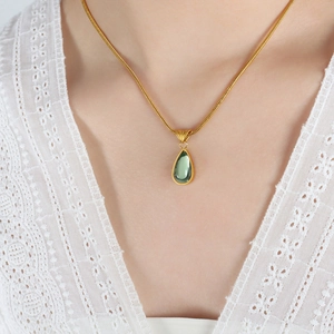 Vintage gold snake chain necklace with teardrop green stone pendant on lace collar