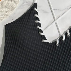 Detail of black ribbed fabric with lace-up eyelet design on a marble background