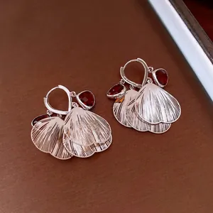 Artistic silver fan-shaped tassel earrings with deep red faceted gemstones on dark base