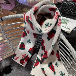 Detail of Christmas knit scarf featuring festive patterns on soft off-white fabric