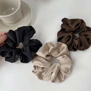 Three satin hair scrunchies in black, champagne, and dark brown colors with silk shine