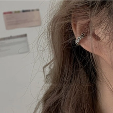 Close-up of a silver snake ear cuff with geometric facets worn on the upper ear cartilage