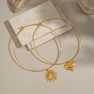 18K gold plated titanium steel necklaces with sun and heart pendants on textured stone