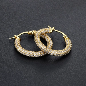 Macro view of gold hoop earrings featuring micro-paved white zircons on black background