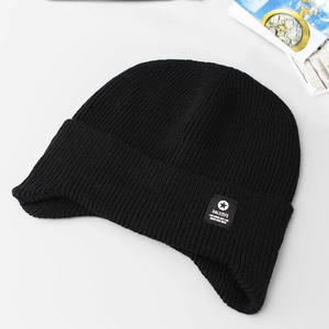 Close-up of black ribbed knit beanie with branded ear protection flap and woven label