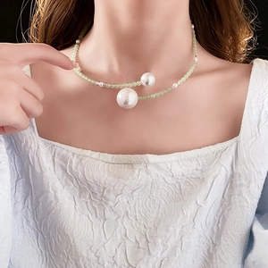 Detail of elegant beaded necklace featuring white pearls and translucent green beads on model