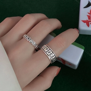 Close-up of vintage silver mahjong rings with Chinese characters on a green table