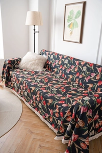 Macro shot of thick jacquard sofa throw featuring red tulip floral patterns and white fringe