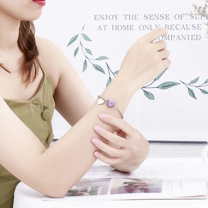 Minimalist stainless steel heart bracelet with purple gemstone worn by a model