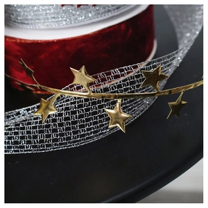 Macro shot of silver mesh ribbon with gold star accents for DIY Christmas tree floral design