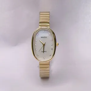 Detail of oval golden watch case with shimmering shell dial and crystal hour markers