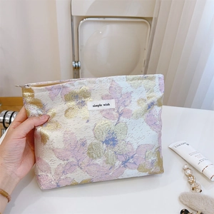 Détail de la trousse cosmétique en jacquard floral avec étiquette simple wish et zip doré
