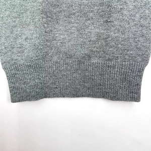 Off-shoulder grey knit sweater showing high-quality ribbed hem and fine wool texture