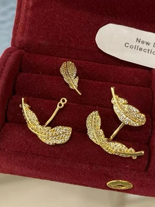 Detailed macro view of gold feather earrings with zircon inlay in a red velvet box