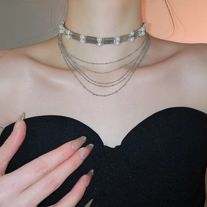 Détail d'un collier de perles multicouche avec chaînes argentées sur un cou de femme élégant