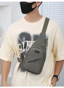 Detail of military green canvas sling bag with SPORT logo patch and front zipper pocket