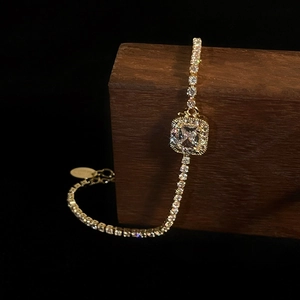 Luxurious gold tennis bracelet with a halo square-cut zircon stone on dark wood base