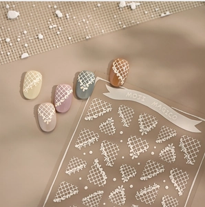 Detailed macro of 3D embossed white lace and grid pattern nail art stickers on samples