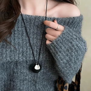 Close-up of heart pendant leather necklace with TAKE IT EASY engraving on grey sweater