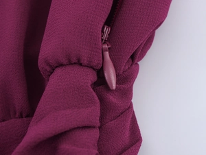 Vue macro de la fermeture éclair invisible et du tissu bordeaux texturé de la robe