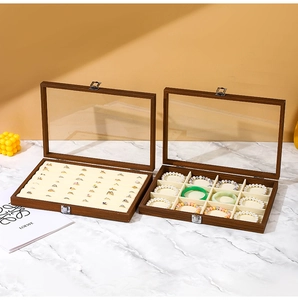 Detail view of walnut wood jewelry box featuring clear glass lid and velvet organizers