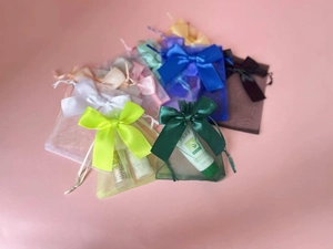 Detailed view of colorful organza gift bags with drawstring ribbons on pink surface
