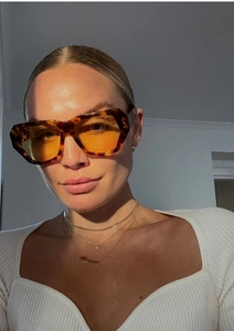 Detail view of tortoiseshell oversized sunglasses with yellow lenses and rivet accents
