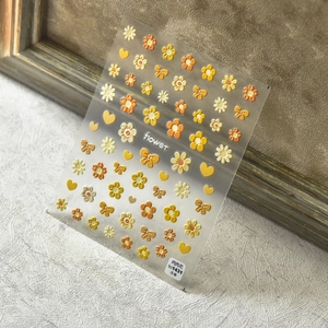 Macro shot of 5D embossed sunflower and bow nail stickers with 3D relief texture