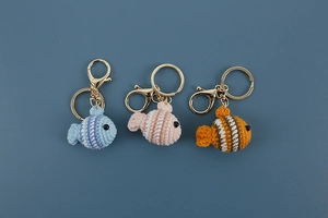 Close-up of three handmade crochet clownfish keychains in blue, pink, and orange patterns