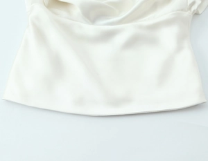 Detailed view of white satin blouse with elegant back bow and soft fabric textures