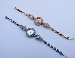 Detail view of gold and silver quartz watches with rhinestone-encrusted floral leaf bracelets