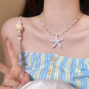 Close-up of a colorful beaded summer necklace featuring a white starfish charm on a model