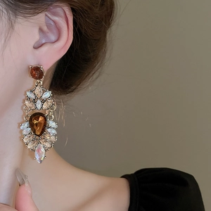 Macro shot of vintage palace style drop earring with amber crystals on model's ear
