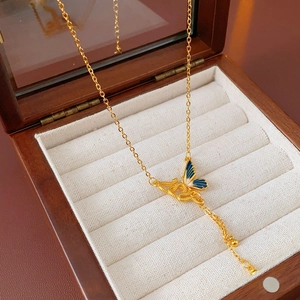 Dettaglio della collana a nodo dorato con ciondolo a farfalla blu in scatola regalo