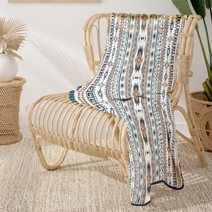 Detail of bohemian knit blanket with tribal patterns draped on a rattan chair