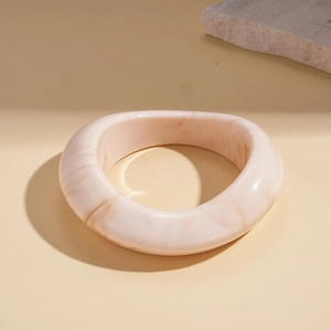 Detail of cream marbled resin cuff bracelet with a wide geometric open design