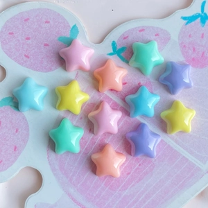Close-up of colorful resin star charms in pastel colors on a strawberry pattern tray