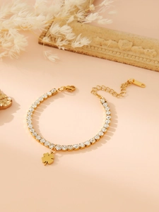 Detailed close-up of golden tennis bracelet featuring square zircons and clover charm