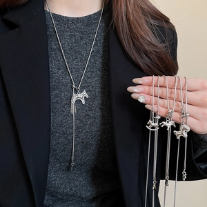 Macro shot of silver horse pendant necklaces with zircons and sleek snake chain on a model