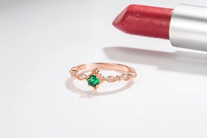 Close-up of S925 rose gold ring with emerald green gemstone and small diamonds